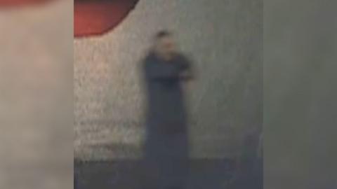 Grainy CCTV shows man standing in a dark street pointing a gun