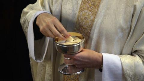 A priest holding communion wafers