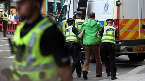 A protester is lead away by police officers on Lothian Road, Edinburgh, during a demonstration by climate change activists