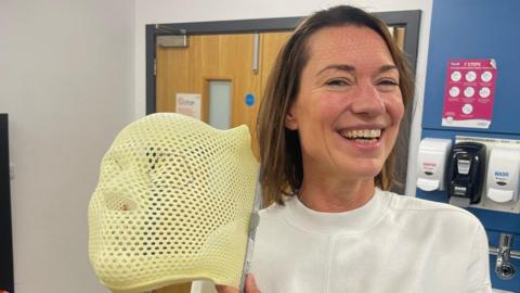 Jo Fuller holding her radiotherapy mask.