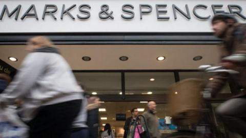 Shoppers cycling and walking past an M&S store