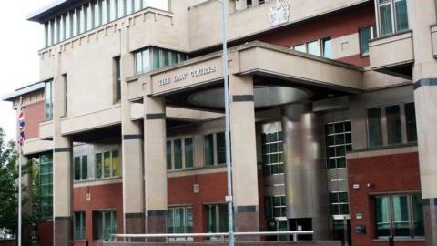 The exterior of Sheffield Crown Court. It is a redbrick and beige building with pillars overhanging a steel entrance.