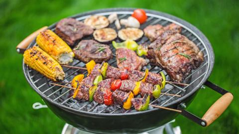 A barbecue with meats, kebabs and vegetables being cooked