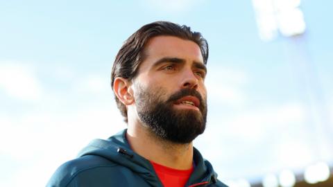 Elliot Lee wearing a blue hoodie with a red t-shirt underneath 