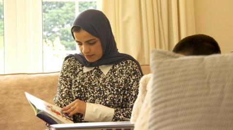 Dr Sumaiyah Hayat reading a book to her son