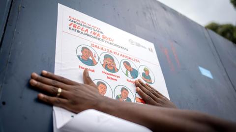 A staff with the non-governmental organization AGIR-RDC that promotes medical access, displays a poster describing preventive measures against Ebola, in Goma, North Kivu, Democratic Republic of Congo