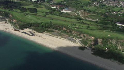 An aerial image of Carlyon Bay with green grass behind it.