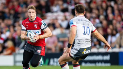 Ollie Thorley holding a ball with two hands and running
