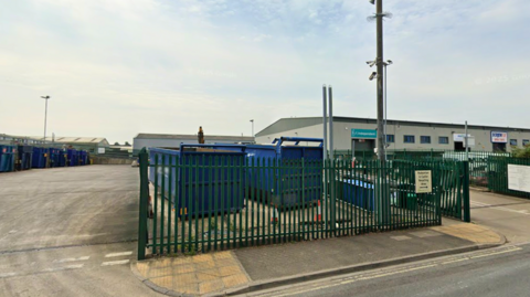 A waste disposal centre with large blue bins on an industrial estate.