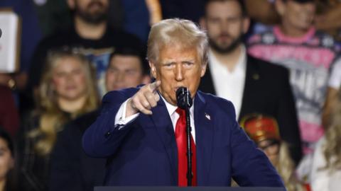 Donald Trump, wearing a blue suit and red tie, gestures with his right hand as he speaks at an event in Las Vegas on 24 January