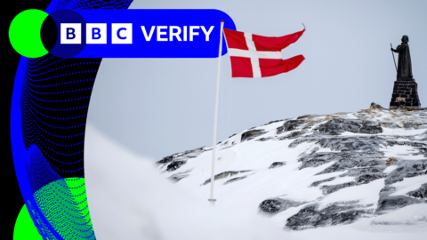 A Danish flag on a snowy hill in front of a statue 