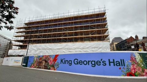 King George's Hall covered in grey plastic sheeting and scaffolding 