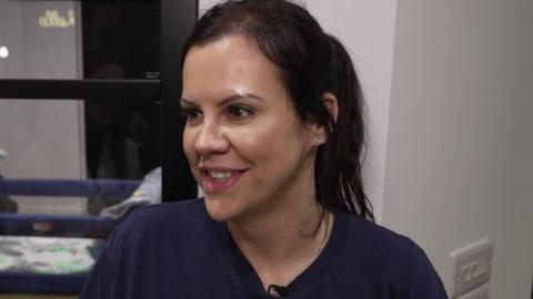 Katie, who has medium length brown hair and is wearing a blue top