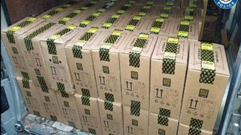 Dozens of boxes with black and yellow tape on them.