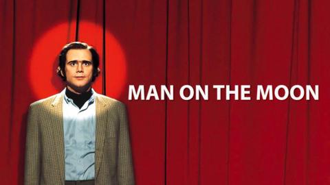 Jim Carrey as Andy Kaufman. He's standing in front of a red curtain with a spotlight shining on his face. text by him reads 'Man on the moon'