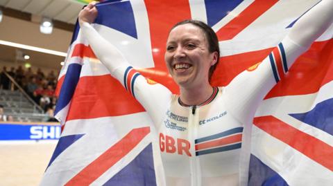 Anna Morris smiles while holding a Great Britain flag