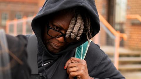 Janice Nix is pictured arriving at court. She is wearing a navy blue hoodie and has a bag strap over her shoulder.