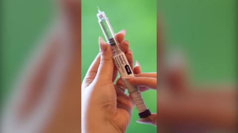 A woman's hands hold an injection needle containing the weight-loss drug Mounjaro.
