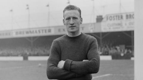 Black and white photo of Ron Baynham with short hair on a football pitch