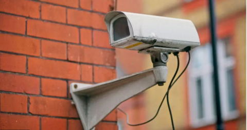 Generic CCTV camera attached to a red brick wall.