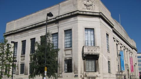 The Central library is a white stone built building with large windows and ornate stonework