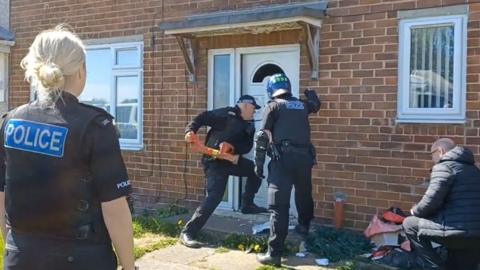 Officers breaking down a door