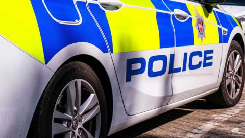 A yellow and blue police car with the word police in bold font on the side. 