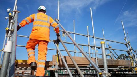 HS2 construction worker wearing hi-vis clothing climbing scaffolding