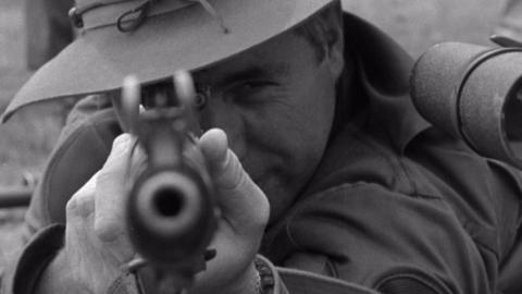 A marksman aiming at his target with a rifle.