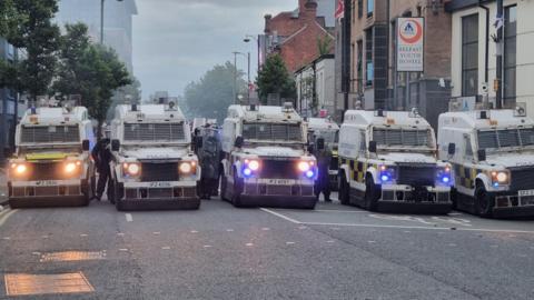 PSNI vans lined up side by side on a road in Belfast city centre