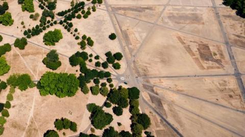 An aerial view of London's Hyde Park showing a few trees and parched land
