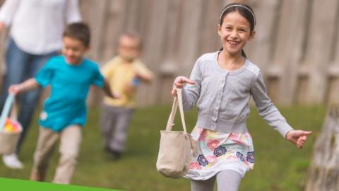 Girl in a grey cardigan and colourful dress and grey leggings running with a bag in her hand 