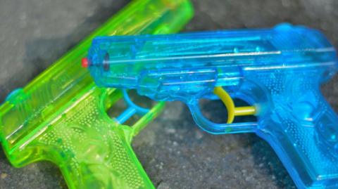 Two small water pistols - a green and blue one on a grey surface