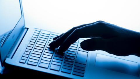 A stock image of a hand on a laptop keyboard