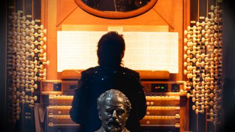 A woman sits at the organ in the Royal Albert Hall.