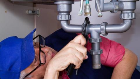 Man with wrench under sink