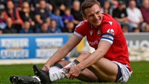 Paul Mullin sits on the pitch