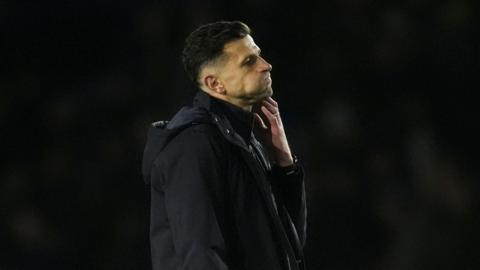 John Mousinho puffing out his cheeks and holding his hand to his chin after a match