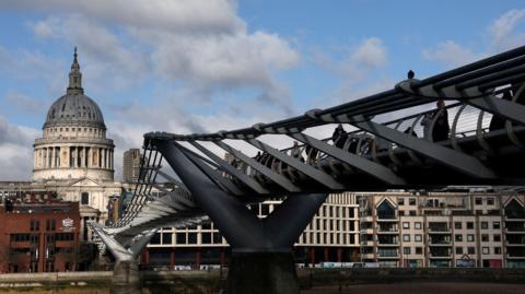 People cross the Millenium Bridge with St Paul's Cathedral in the background. 