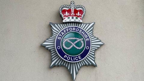 A close-up of a crest on the wall of a building. The crest has the words Staffordshire Police in a circle, with an image of a  knot in the middle