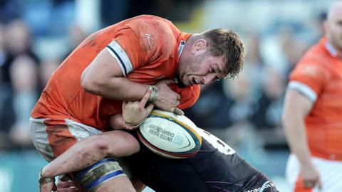 Jamie Hodgson, holding the ball, is tackled by an Ospreys player during a URC match last season