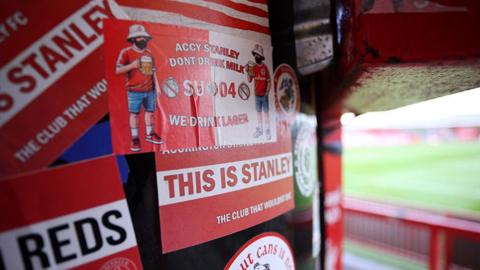Lots of red-and-white Accrington Stanley stickers on a drum inside the stadium 