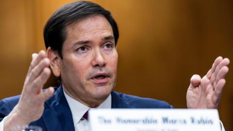 US Secretary of State Marco Rubio motions with both of his hands while he  testifies before a Senate Foreign Relations Committee hearing to examine US policy towards Venezuela on Capitol Hill in Washington DC on  28 January 2026.