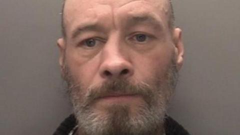 Mugshot of Alan Teague. He has bald head, and a grey and brown beard.