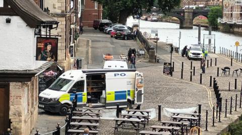Police van and car on the riverside in York.