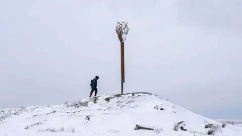 A man walks up to Danby Beacon