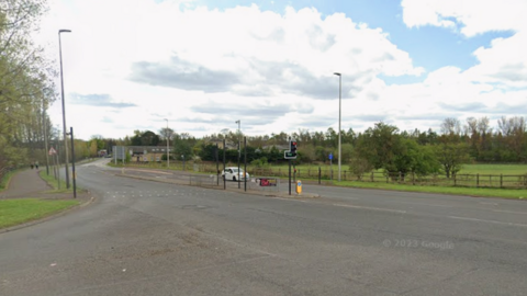 A road junction with a white car sitting at traffic lights