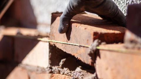 A bricklayer repairs a wall on a domestic property