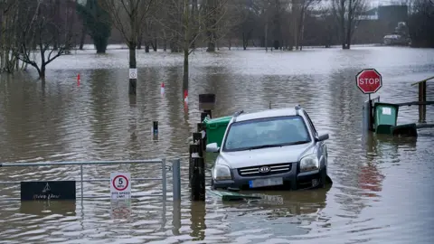 A car is seen against a flooded road during flooding in Yalding, Kent