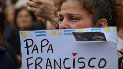 A woman holds a sign at a mass for the healing of Pope Francis in Constitution Square, Buenos Aires, Argentina, on 24 February 2025.